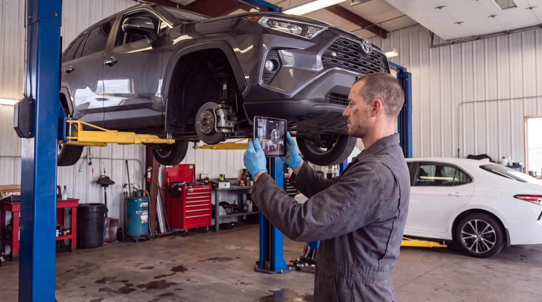 A technician photographs a vehicle on the lift for a digital inspection